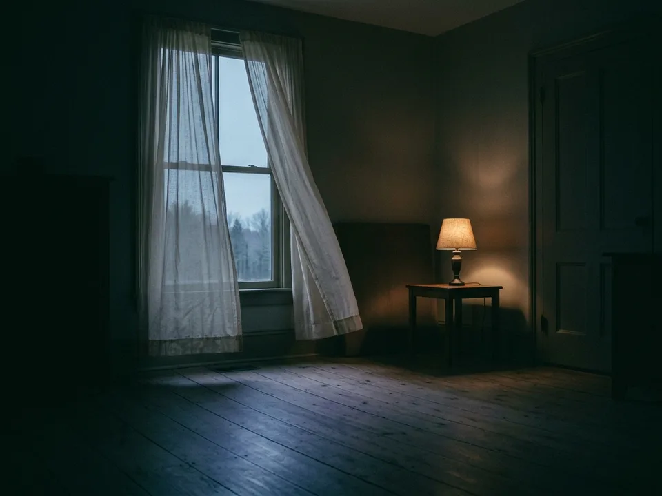 A tall window at dawn, sheer curtains and first light across an empty floor